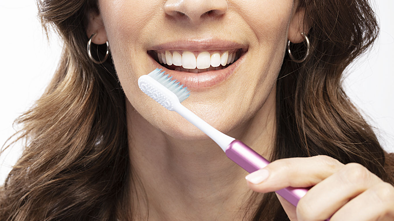 Woman holding a Pink Nada eco-friendly toothbrush