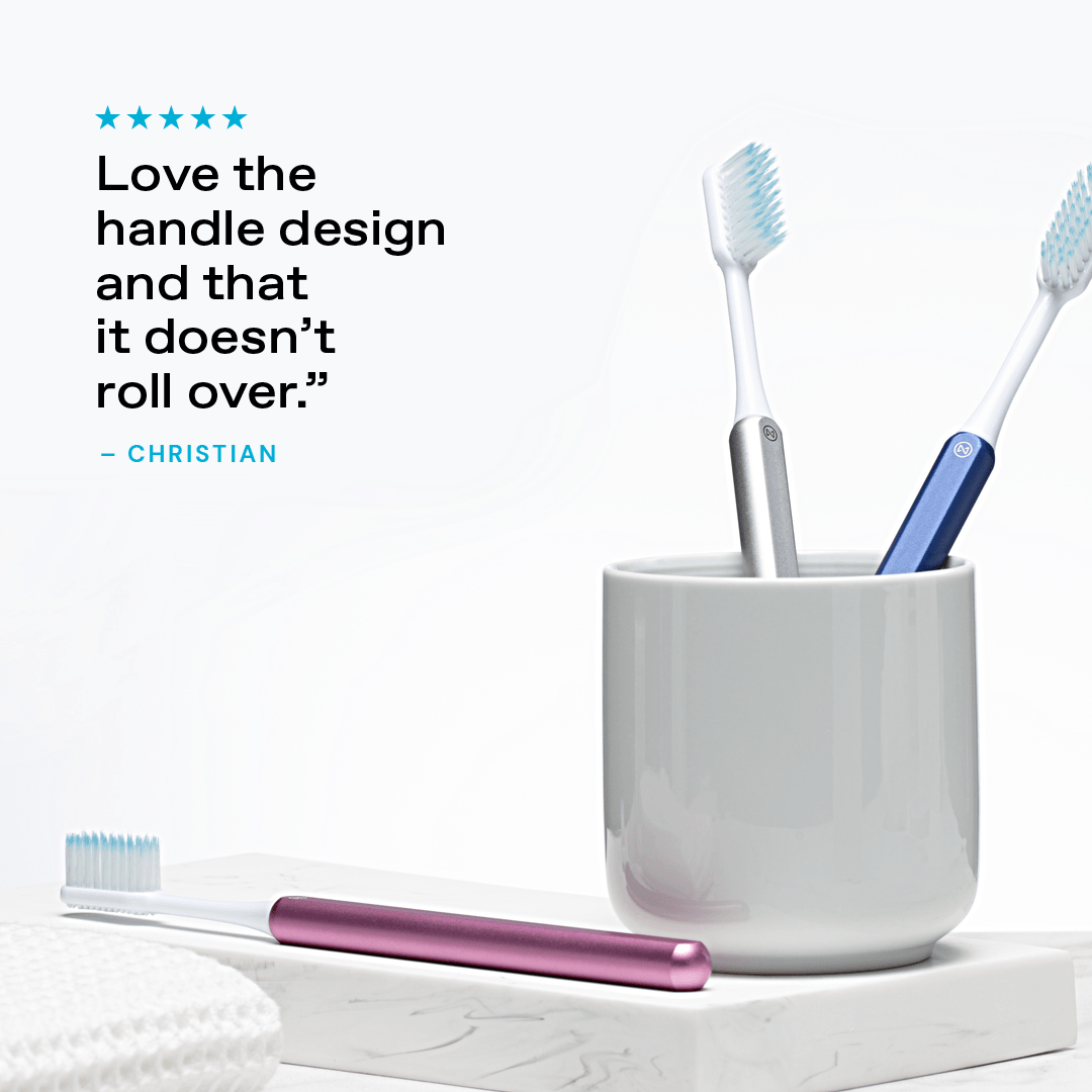 Pink, Silver and Ocean Blue Nada Toothbrushes in a cup with a customer testimonial: "Love the handle design and that it doesn't roll over."