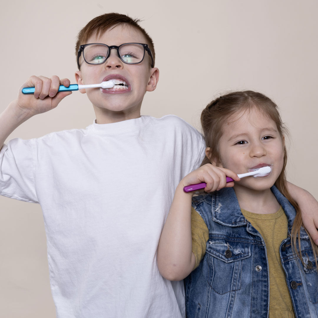Two kids brushing with Blue and Pink eco-friendly Nada Toothbrushes