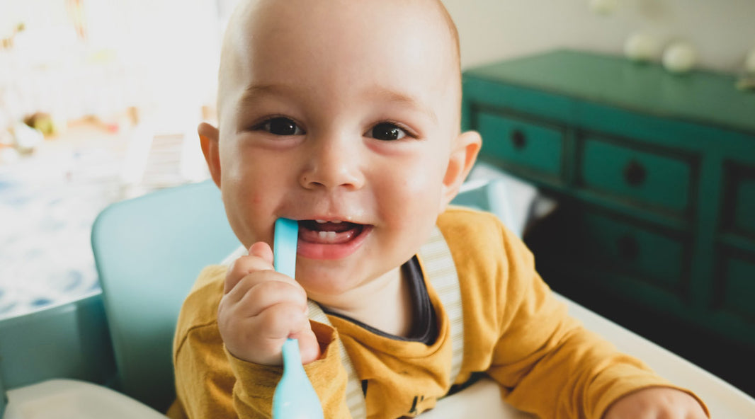 Toddler with baby teeth a spoon in his mouth