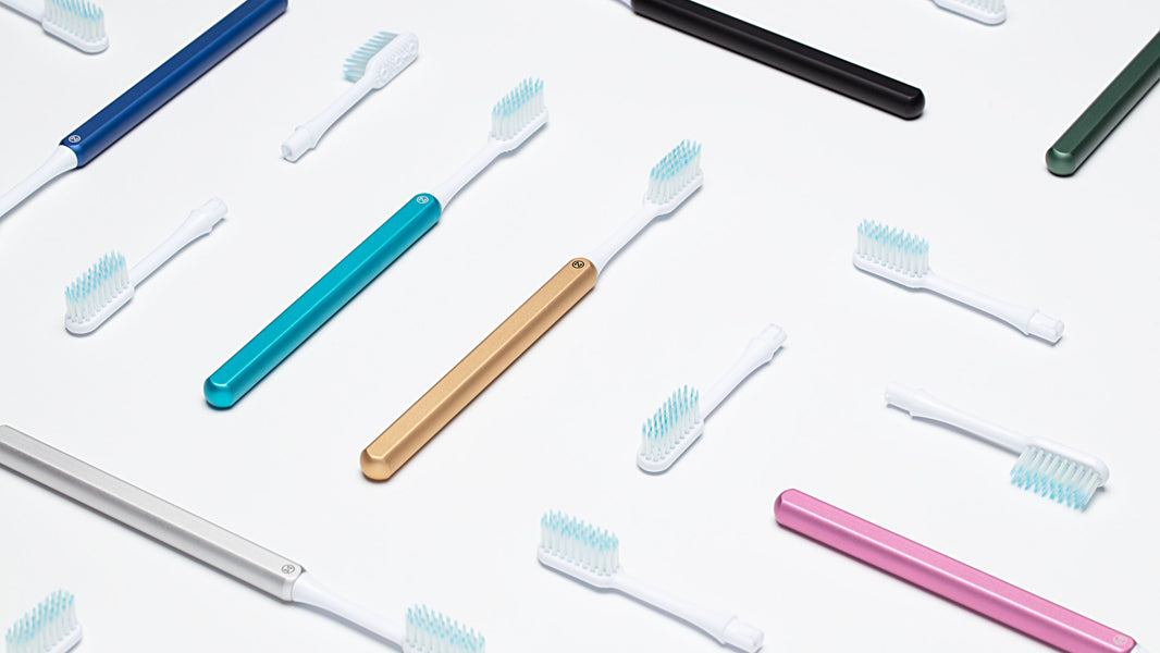 Eco friendly Nada toothbrushes with metal handle and replacement toothbrush heads in various fun colours on a counter