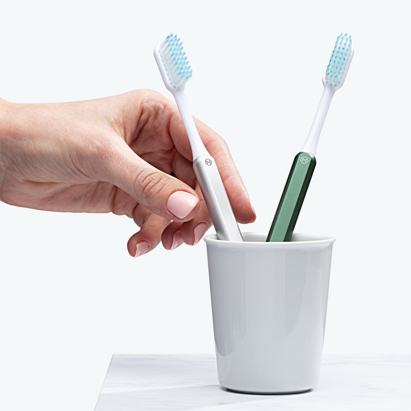 Hand reaching for a Silver Nada toothbrush – the best manual toothbrush