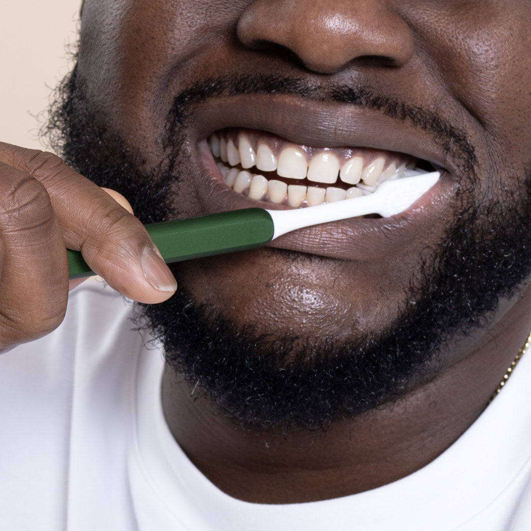 Man brushing his teeth with a Green eco-friendly Nada toothbrush