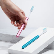 Hand holding a Pink Nada sustainable toothbrush with an Arctic blue toothbrush beside it