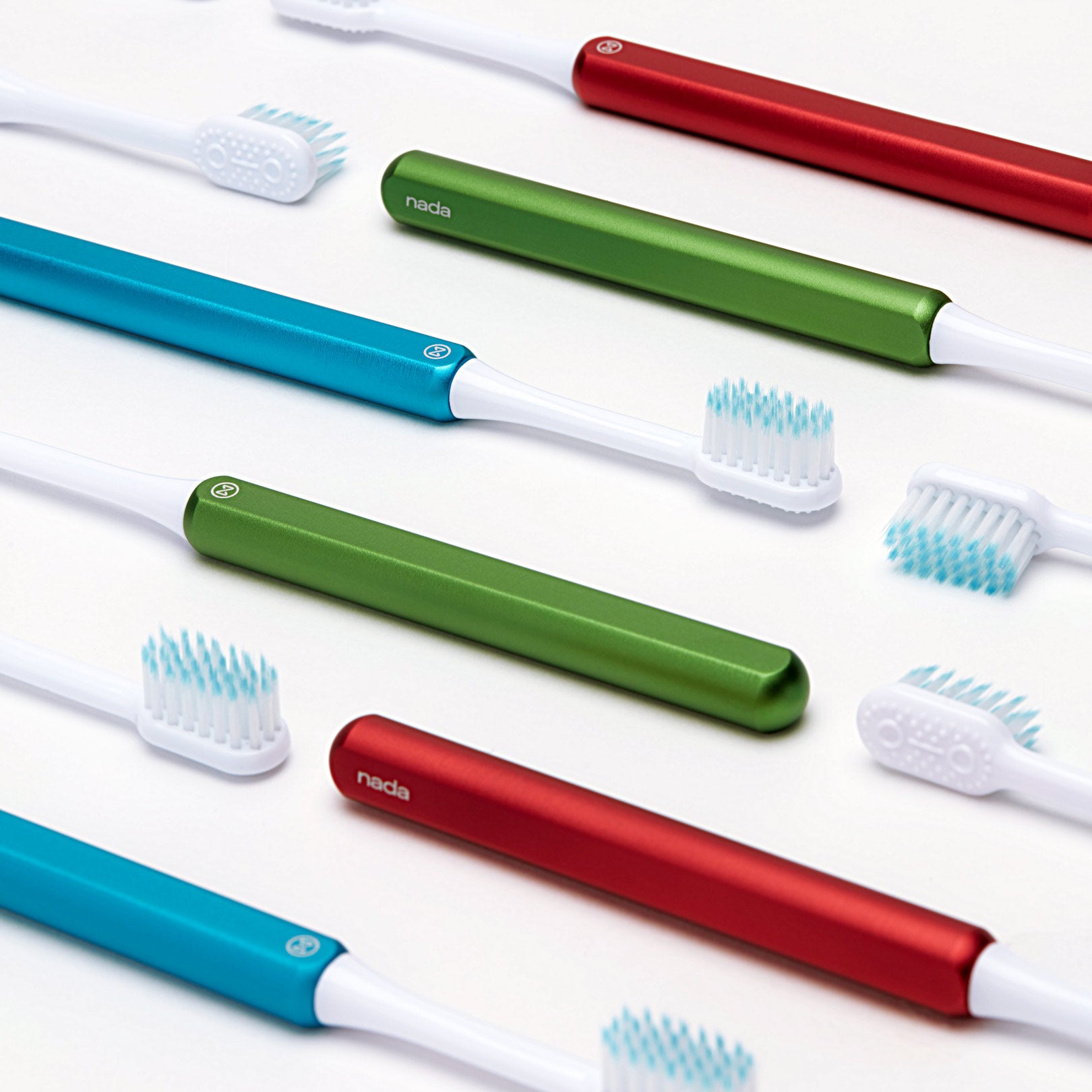 Red, blue and green Nada kids eco friendly toothbrushes laying flat on a counter