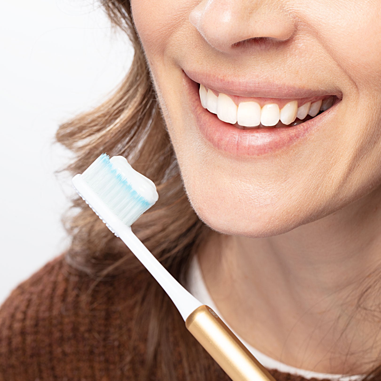 Woman smiling using a Gold Nada toothbrush