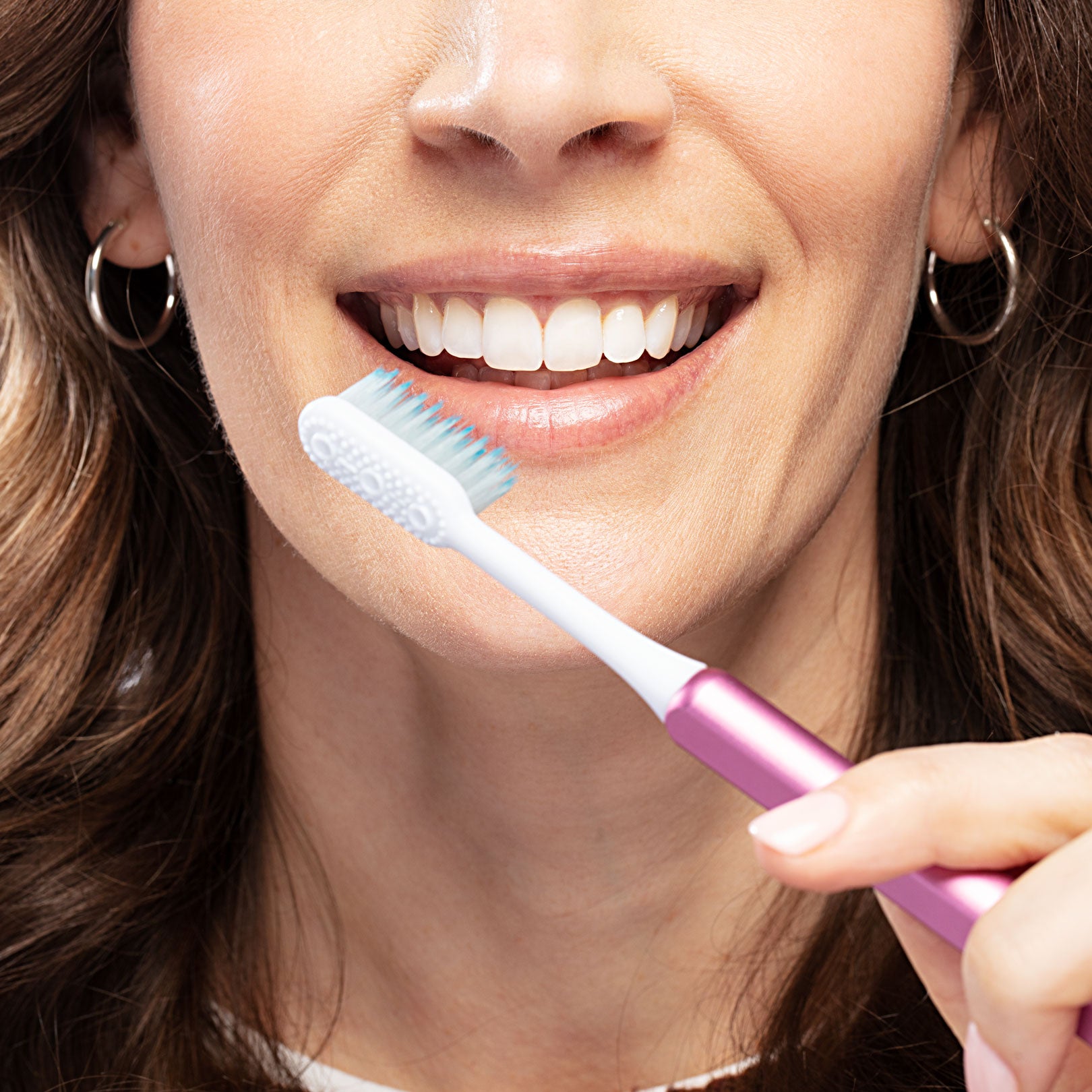 Woman smiling using a Pink eco-friendly Nada toothbrush