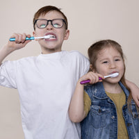 Two kids brushing with Blue and Pink eco-friendly Nada Toothbrushes