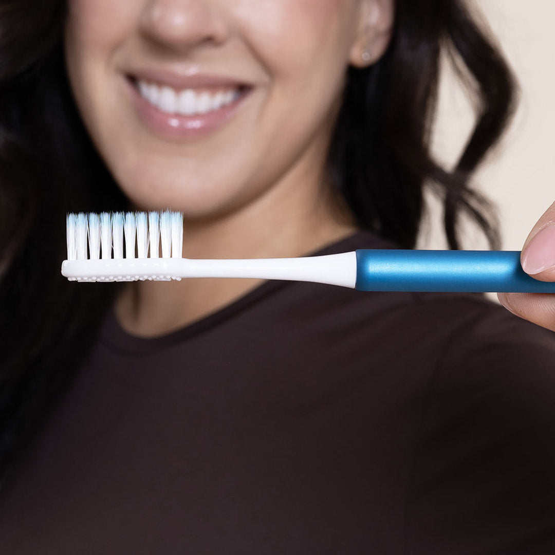 Woman holding an Arctic Blue sustainable Nada Toothbrush with Soft, Floss-tip bristles